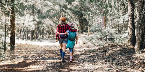 camp leader walks with camper on wooded trail
