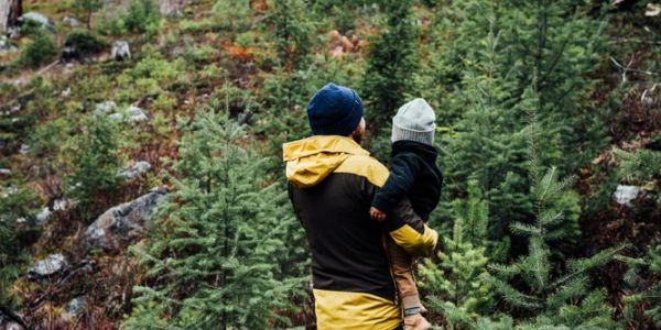father carries child on wooded hillside walk