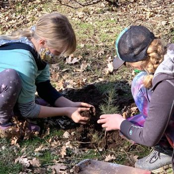two young girls plant trees at Great River